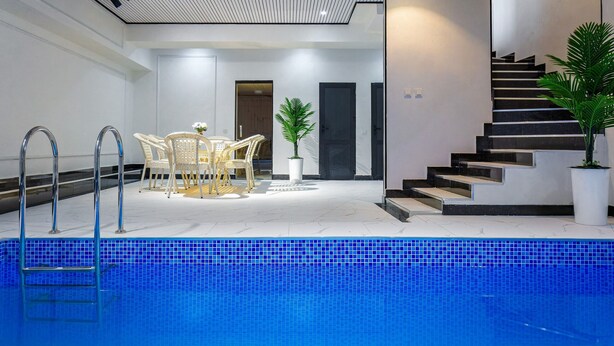 A modern indoor pool area with a dining set, a staircase, and a potted plant. - Astoria Boutique (Tashkent)
