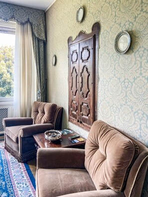 Ein Zimmer mit einem großen Holzschrank, zwei braunen Sofas, einem Couchtisch und einem gemusterten Teppich.