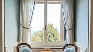 A corner room with a bay window, two upholstered chairs, a small round table, and a radiator. - Villa Marina - Immersed in Nature (Cavaso del Tomba)