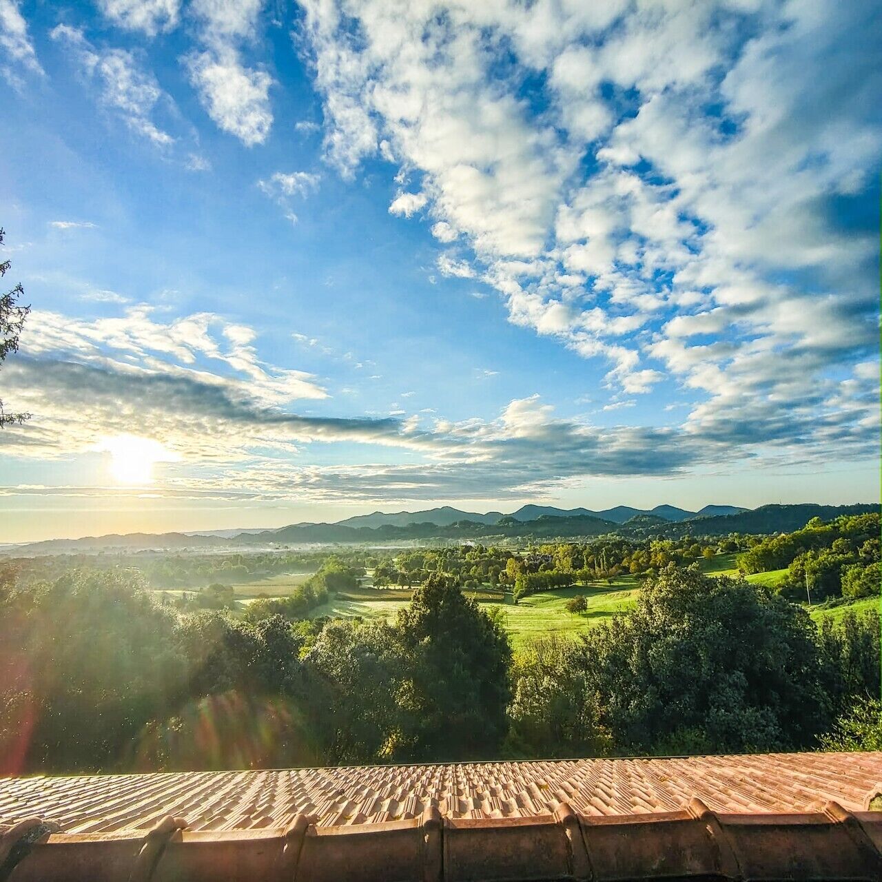 A view from a rooftop terrace with a clear sky and distant mountains.