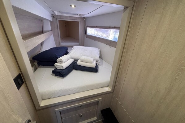 Una habitación pequeña con cama, un ventanal y un banco empotrado.
