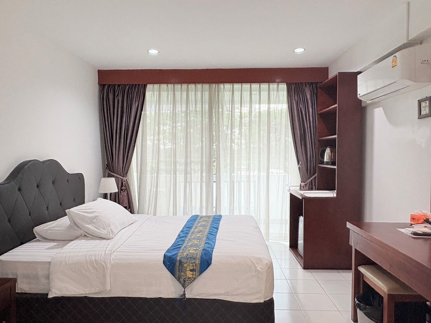 Una habitación de hotel con una cama, un escritorio y una estantería.