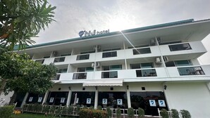 A multi-story hotel with balconies, air conditioning units, and a sign indicating it is a hotel. - NJ INTHAI HOTEL (Khlong Luang)