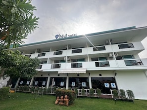 Un hotel de varios pisos con balcones, unidades de aire acondicionado y un letrero que indica que es un hotel.