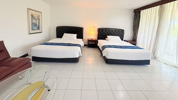 A hotel room with two beds, a chair, a desk, and a window with curtains. - NJ INTHAI HOTEL (Khlong Luang)