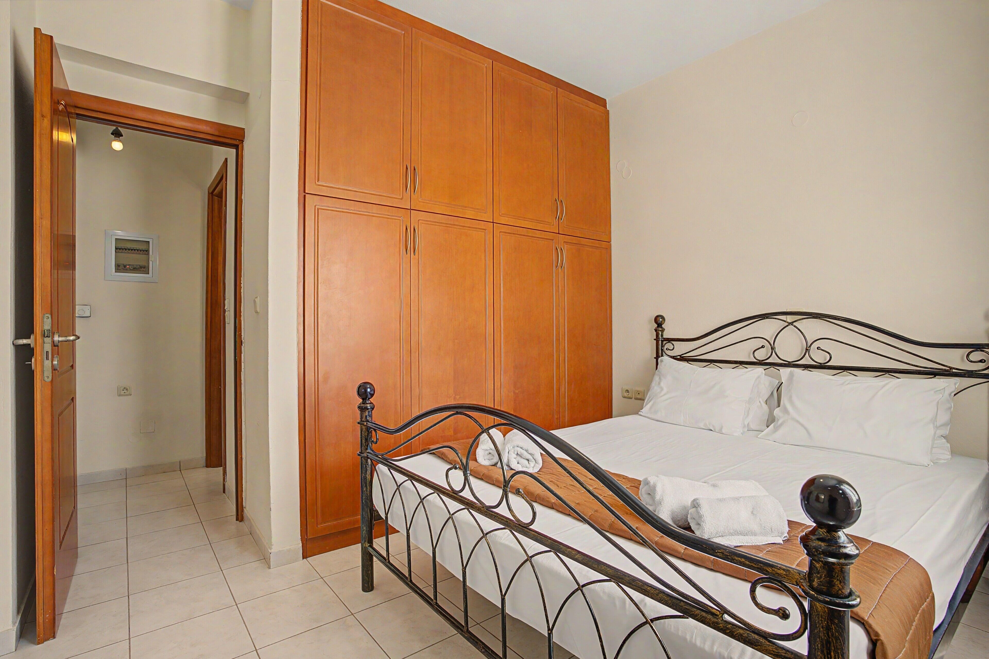 Une chambre à coucher comprenant un lit, une armoire et une porte donnant sur une autre pièce.
