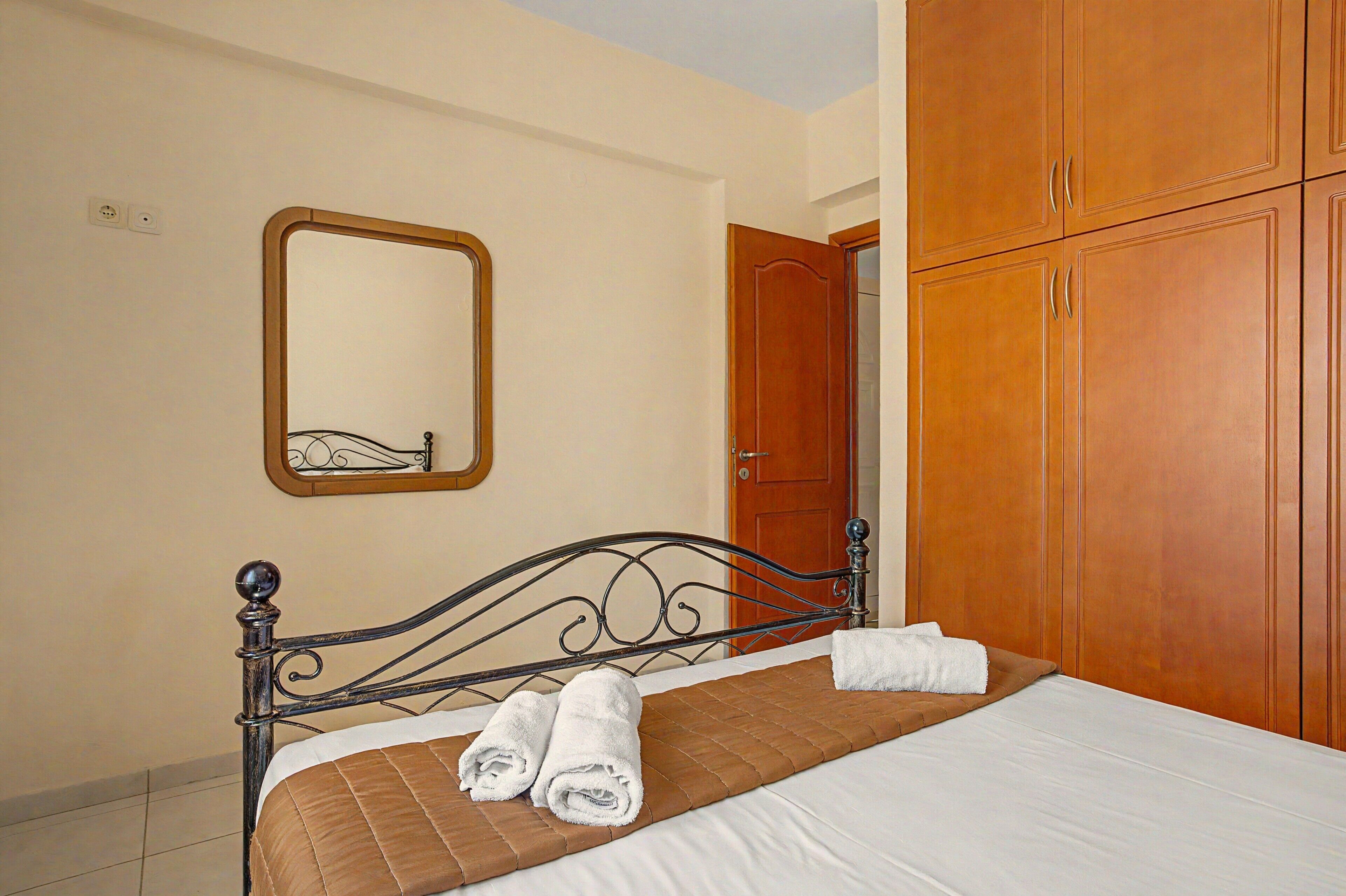 Une chambre à coucher avec un lit, une armoire en bois, un miroir et une porte.