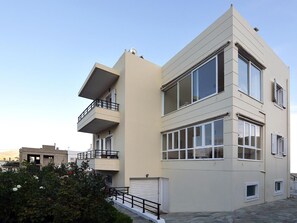 Un immeuble moderne à plusieurs étages, doté de balcons, de grandes fenêtres et d’un garage.