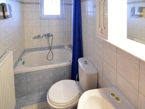 Une salle de bain avec une baignoire, des toilettes et une fenêtre.