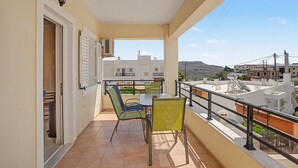 Een balkon met een tafel en stoelen, uitzicht op de stad, en een gebouw met een balkon.