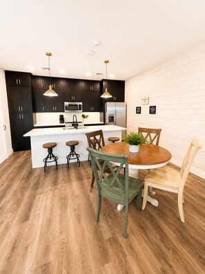 A modern kitchen with dark cabinets, stainless steel appliances, and a central island with stools. - 3 BD Family Home | Extd Stays | Pets Ok (Aransas Pass)