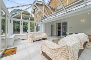 A conservatory with two sofas, a radiator, and a Netflix sign.