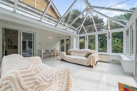 A spacious room with a glass ceiling, a sofa, a chair, and a dining area.. The Thorney Retreat: Peterborough