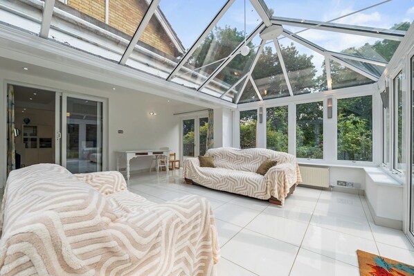 A spacious room with a glass ceiling, a sofa, a chair, and a dining area.