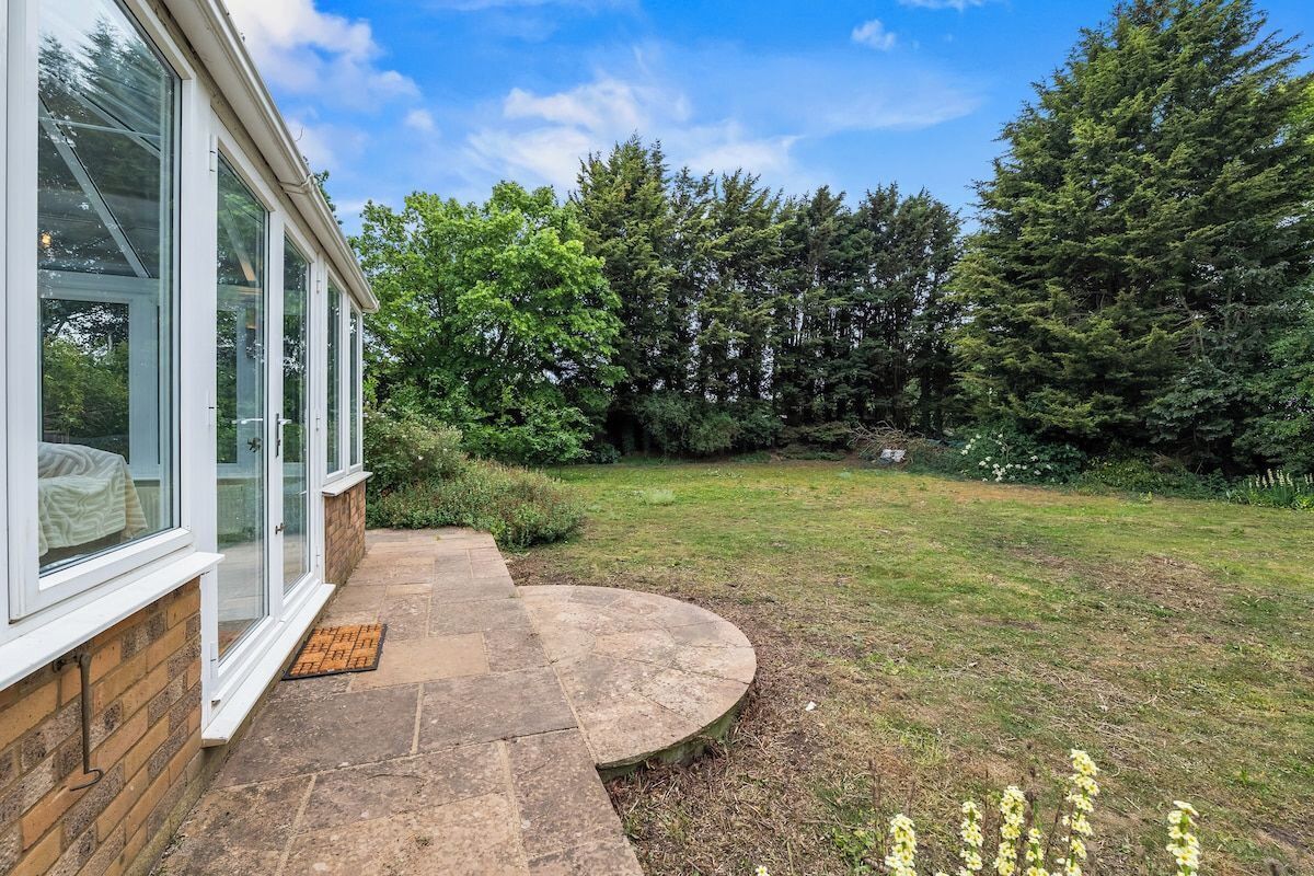 A house with a stone pathway leading to a grassy yard, surrounded by trees.