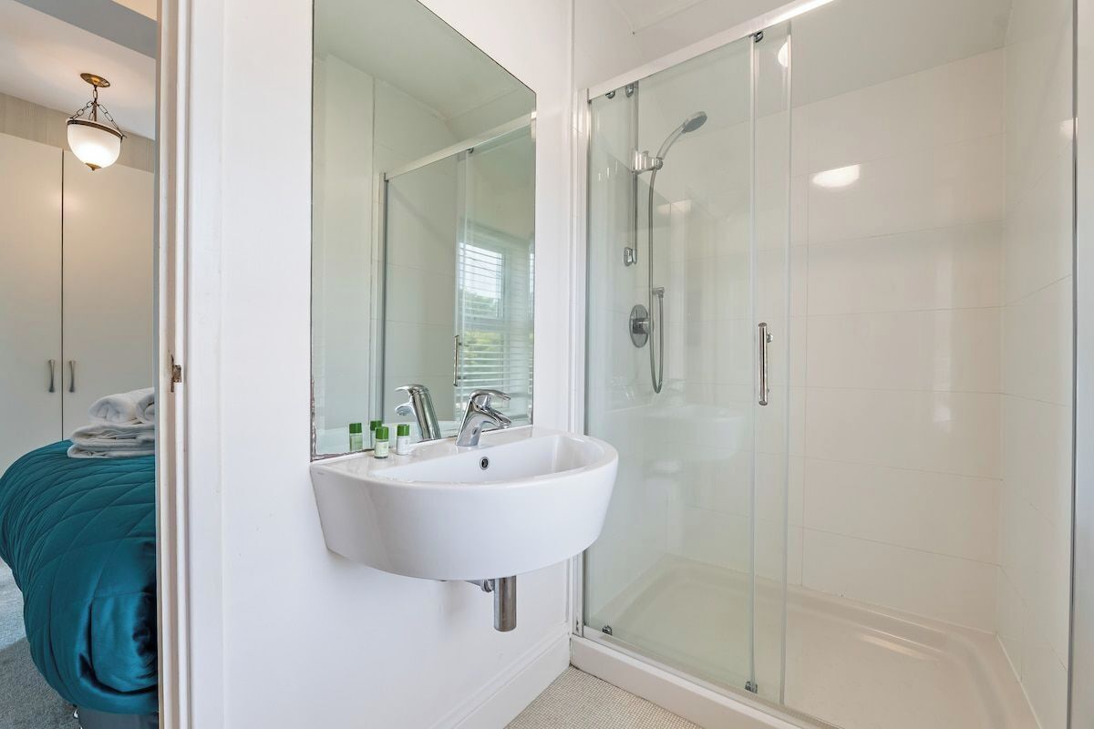Une salle de bain moderne avec une douche à parois de verre, un lavabo blanc et un grand miroir.