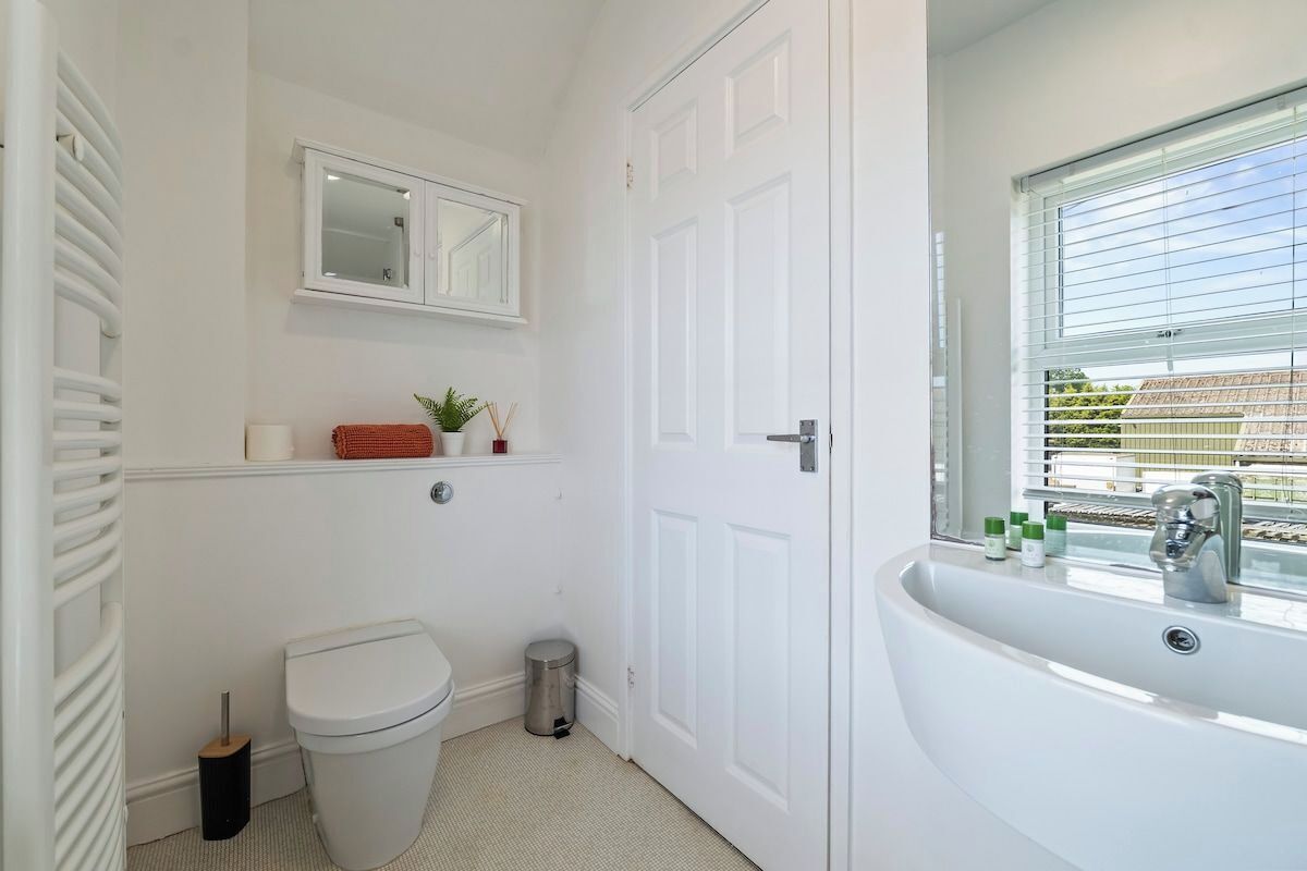 Ein Badezimmer mit Toilette, Waschbecken, Spiegel und Fenster.