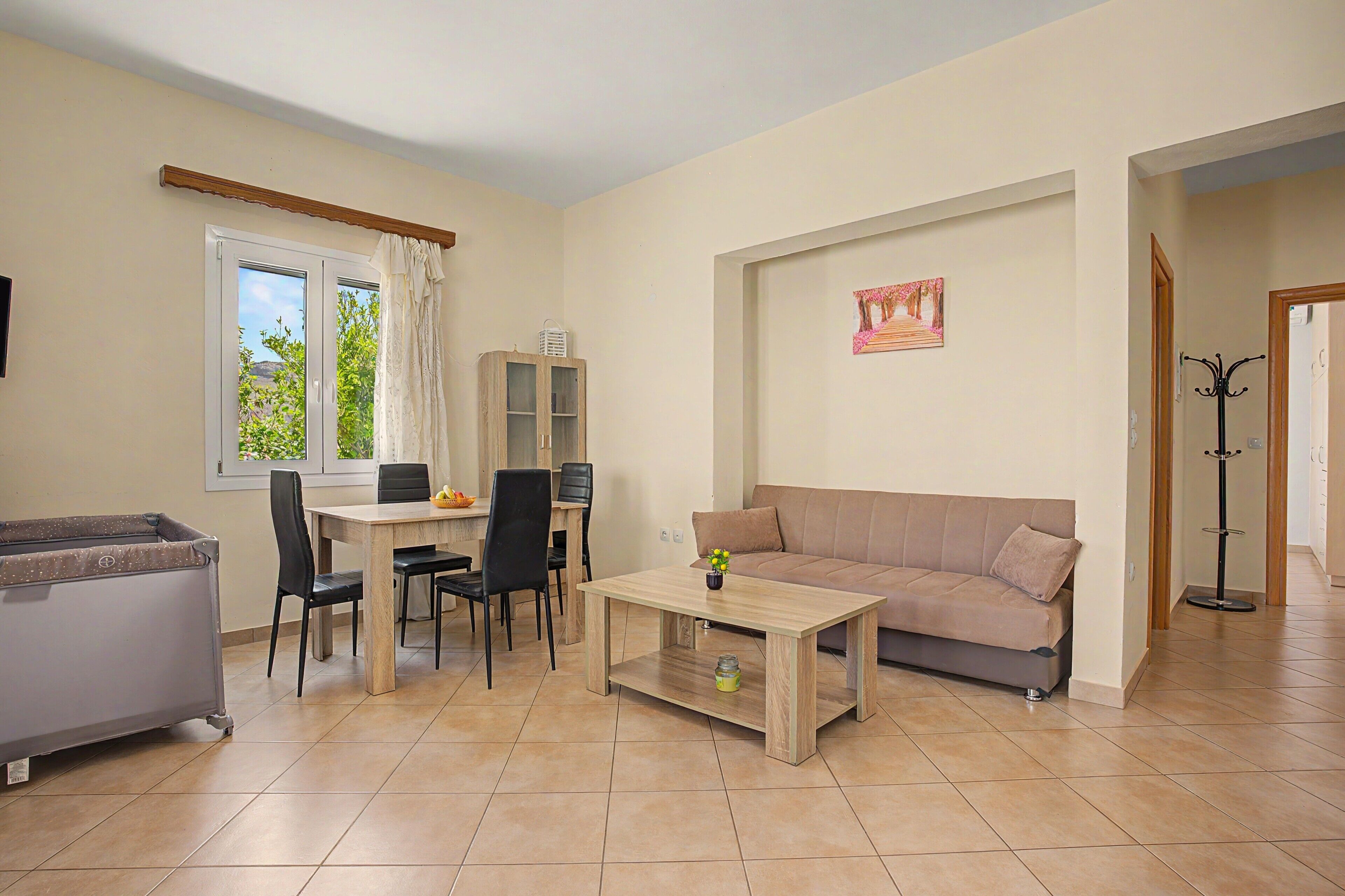 A living room with a sofa, a dining table with chairs, a cabinet, and a window with curtains.
