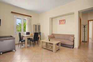 Een woonkamer met een bank, een eettafel met stoelen, een kast en een raam met gordijnen.