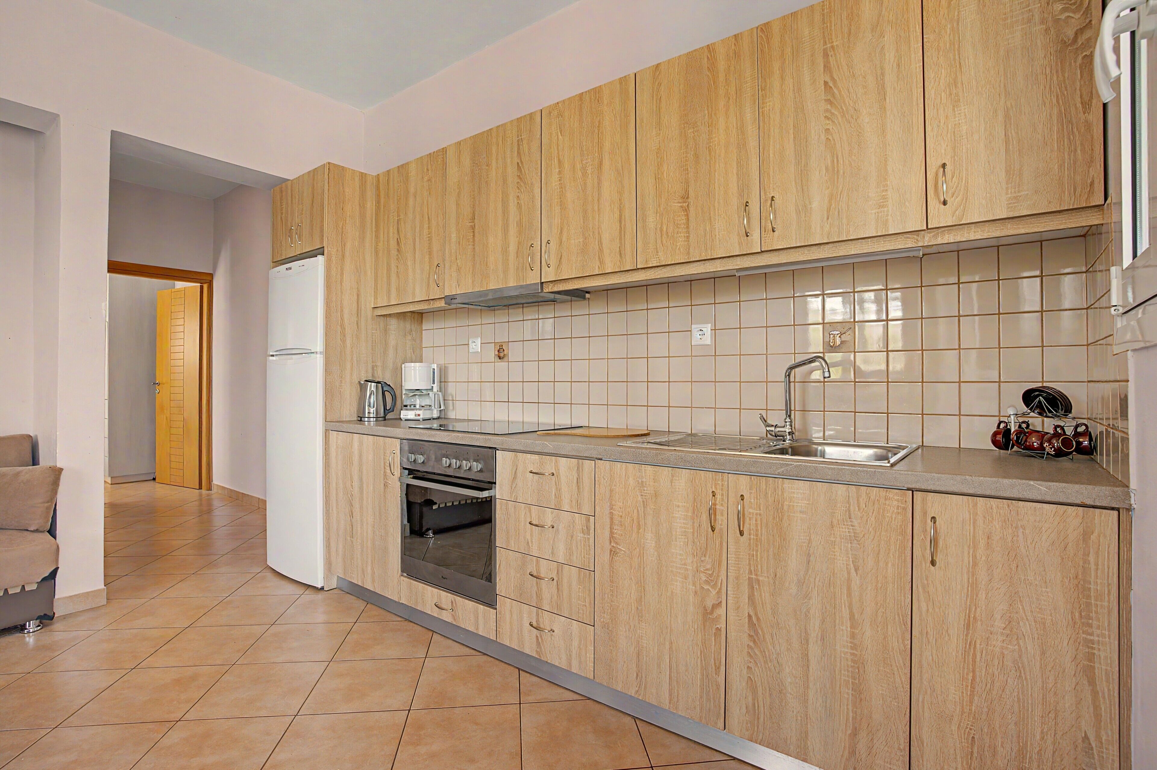 A modern kitchen with wooden cabinets, a stainless steel sink, and a built-in oven.