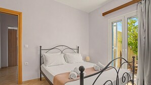 Een slaapkamer met een bed, een raam met gordijnen, een deur en een betegelde vloer.