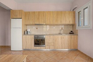 A kitchen with wooden cabinets, a stainless steel refrigerator, a built-in oven, and a tiled backsplash.