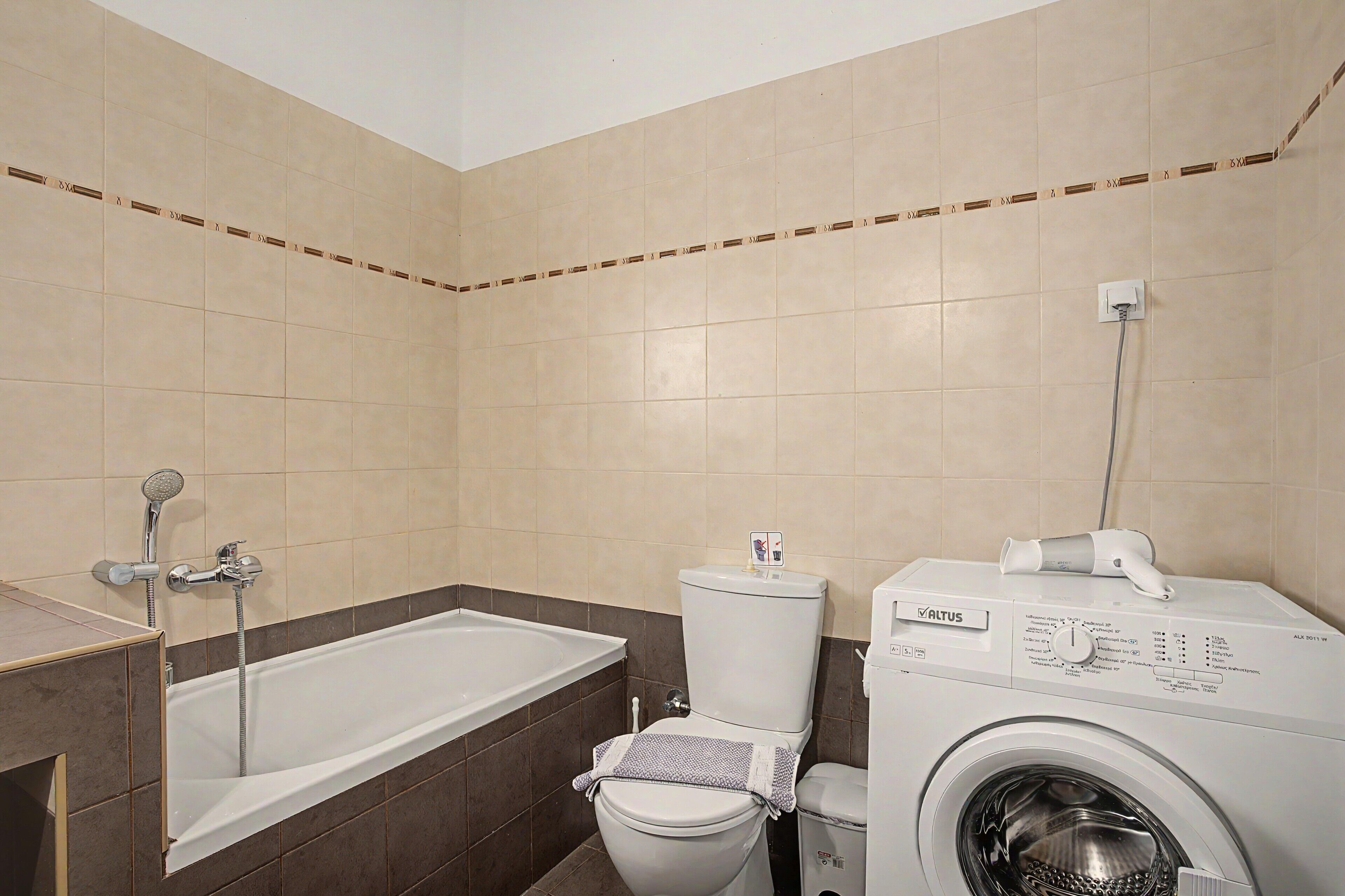 Ein Badezimmer mit Badewanne, Toilette und Waschmaschine.