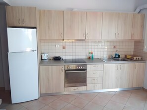 Une cuisine moderne avec des meubles de couleur bois clair, un réfrigérateur blanc, une cuisinière et un évier.