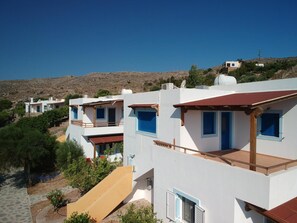 Uma área residencial à beira-mar, com edifícios brancos, persianas azuis e céu claro.