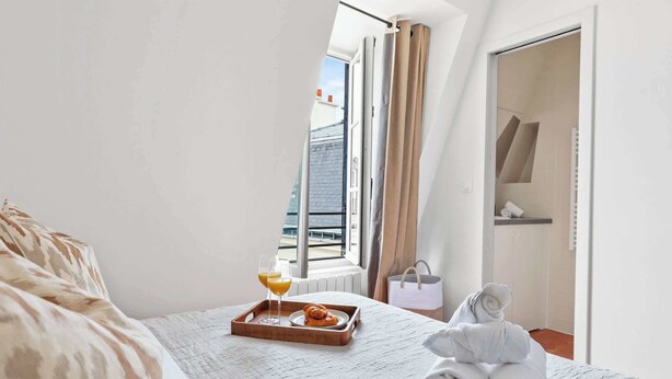Ett hotellrum med en säng, ett bricka med frukost, en handduk och utsikt över omgivningarna.