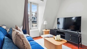 Ett modernt vardagsrum med en soffa, en tv och ett litet sidobord.