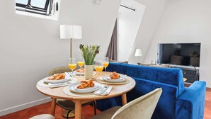 En matplats med ett runt bord, en blå soffa och en tv.