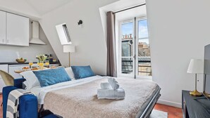 Ett hotellrum med en säng, ett skrivbord med frukost, ett fönster med utsikt och en balkong.