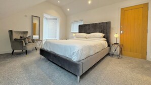 Ein Schlafzimmer mit einem großen Bett, einem Sessel, einem Spiegel und einer Tür.
