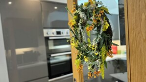 Eine moderne Küche mit Holztür, einem Edelstahl-Kühlschrank und einem eingebauten Backofen.