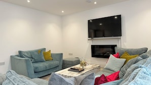 Ein modernes Wohnzimmer mit einer grauen Sofagarnitur, einem Couchtisch und einem flachbildfernseher, der an der Wand befestigt ist.
