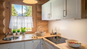 A kitchen with a wooden interior, white cabinets, a sink, a stove, and a window with a view of trees. - Holiday Home With a Terrace and Mountain Views (Koscielisko)