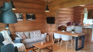 A log cabin interior with a sofa, armchair, dining table, and a kitchen area. - Holiday Home With a Terrace and Mountain Views (Koscielisko)
