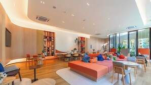 A modern interior with a curved ceiling, a central seating area with a sofa and chairs, a dining area, and a bookshelf. - Modern Condo with Pool View D Condo Phuket C175 (ตำบล กะทู้)