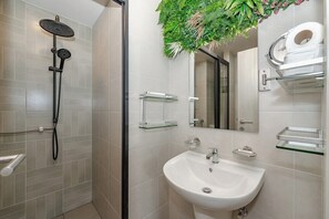 Un baño con ducha, lavabo, espejo e inodoro.
