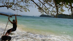 A person on a tire swing over a beach with clear water and distant islands. - Modern Condo with Pool View D Condo Phuket C175 (ตำบล กะทู้)