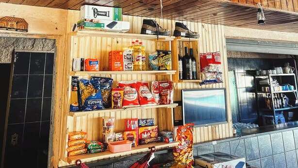 A rustic wooden interior with a wooden sign, shelves stocked with snacks, and a Texas flag. - Camping Mairiporã (Mairiporã)