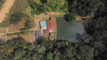Vista aérea de uma propriedade com piscina, área cercada e um corpo d'água.
