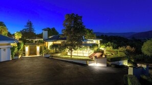 Una casa moderna amb una entrada de cotxes, vestíbul ben il·luminat i jardí paisatjista.