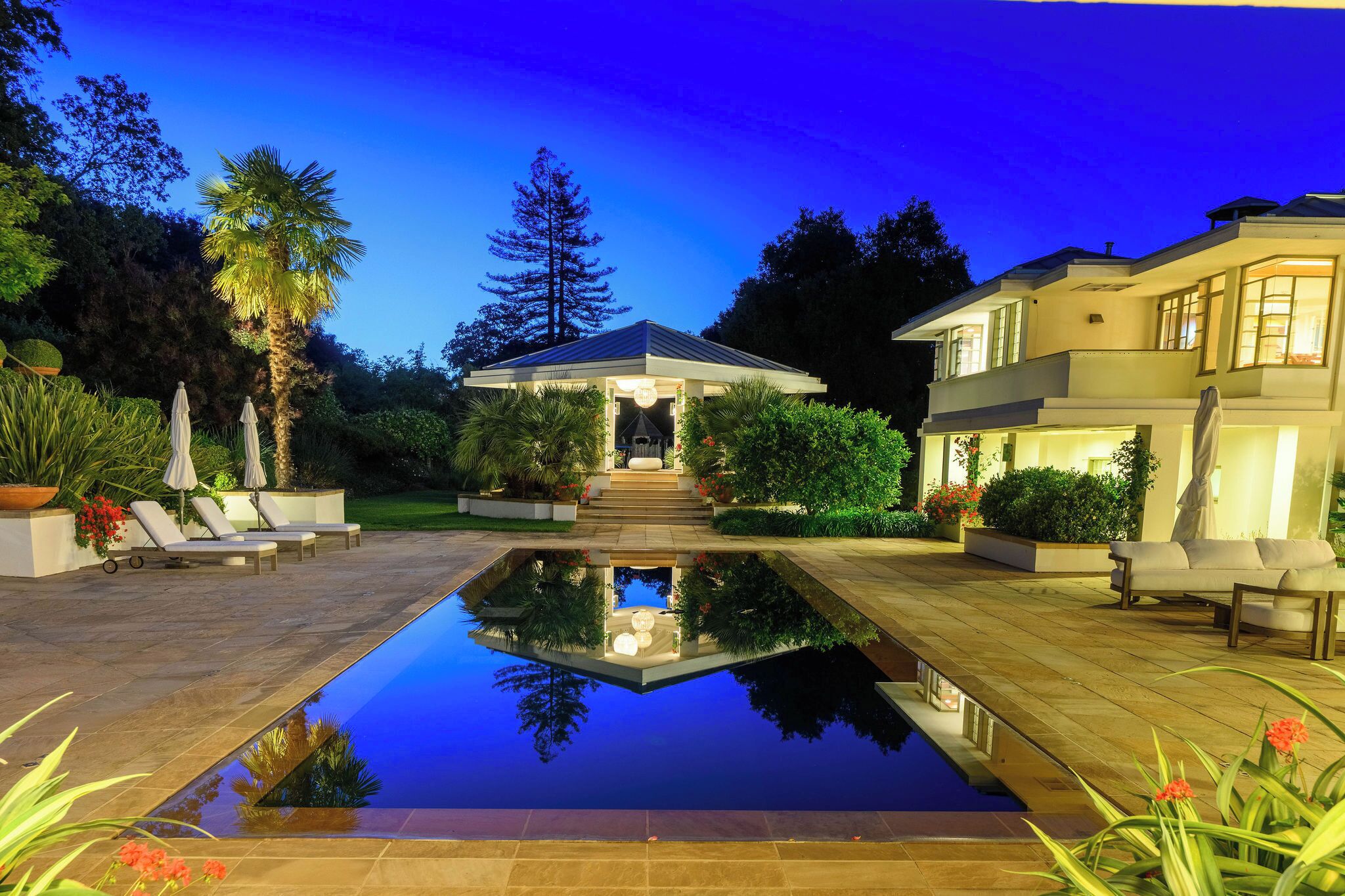 Una casa moderna con piscina, area salotto esterna e giardino curato.