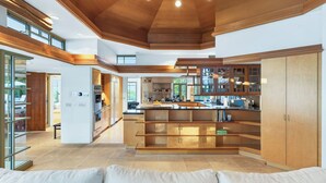 A spacious kitchen with wooden cabinetry, a central island, and a dining area with a sofa. - Frank Lloyd Wright-Inspired Healdsburg Estate (Healdsburg)