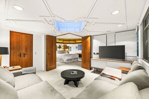 Et moderne hotelværelse med en sofa, et rundt sofabord, et fjernsyn og en seng.