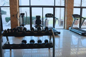Une salle de sport équipée de matériel d’exercice, notamment des tapis de course et des haltères.