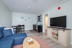 Ein Wohnzimmer mit einer Couch, einem Fernseher und einer Küchenzeile.