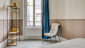 A room with a bed, a chair, a wardrobe, and a window with curtains. - Lola Homes " Contemporary and warm apartment " (Puteaux)